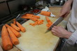 A cook cut carrots in the kitchen of a restaurant