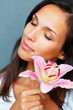 Brunette holding stargazer lily to side of face Brunette holding stargazer lily to side of face