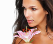 Brunette holding stargazer lily while looking in the distance Brunette holding stargazer lily while looking in the distance