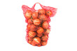 the red vertical standing string bag of bright yellow onions iso