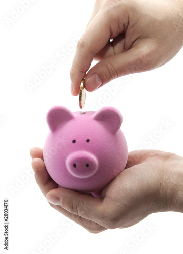 Foto: Putting coin into the piggy bank Putting coin into the piggy bank