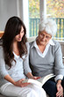 Young woman reading book to elderly woman