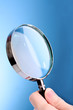 Magnifying glass in woman hand on blue background