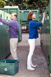 A mid-adult couple recycling glass bottles