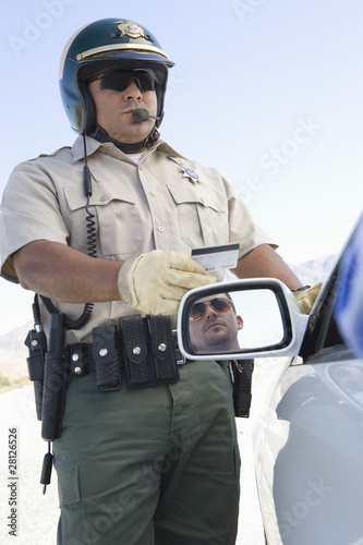 Photo: Highway patrol officer examines driving license Highway patrol officer examines driving license