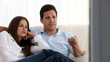 Bored couple changing channels on the sofa ta home