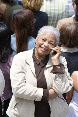 Photo: Woman using mobile phone in crowd Woman using mobile phone in crowd