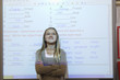 Schoolgirl standing in classroom, projection screen behind her