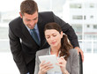 Happy businessman helping a businesswoman working at her desk