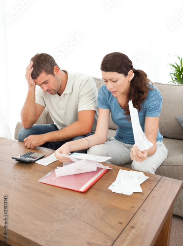 Photo: Worried couple looking at their bills in the living room Worried couple looking at their bills in the living room