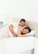 Cute couple lying together in their bedroom during a weekend