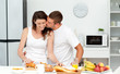 Affectionate man kissing his girlfriend while cutting bread Affectionate man kissing his girlfriend while cutting bread