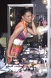 Woman applies makeup in dressing room mirror