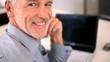 Senior man sitting at desk in front of a laptop