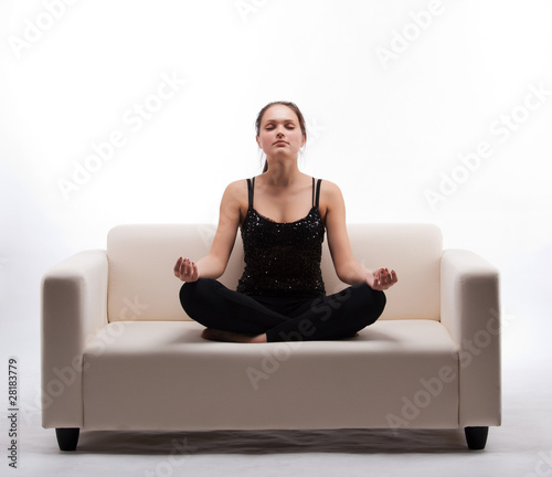 Photo: woman meditating in lotus position on the couch woman meditating in lotus position on the couch