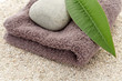 serviette, galet et feuille de frangipanier sur sable blanc
