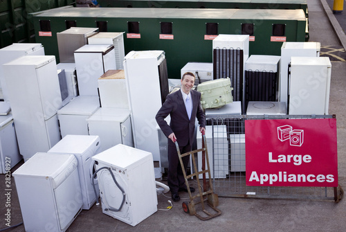 Photo: A businessman standing with a trolley in a recycling center A businessman standing with a trolley in a recycling center
