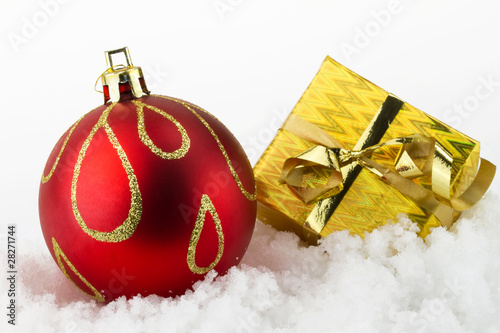 Photo: Christmas gift box and christmas ball on snow Christmas gift box and christmas ball on snow