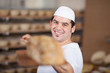 lächelnder bäcker schiebt brot in den ofen