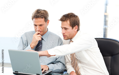 Photo: Two handsome businessmen working together on a project sitting a Two handsome businessmen working together on a project sitting a