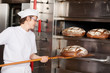 bäckerin holt brot aus dem ofen