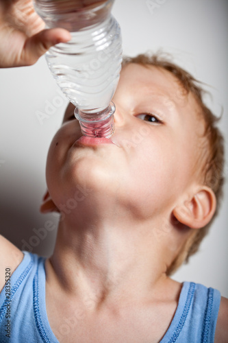 Photo: Quench thirst. The boy is drinking mineral water from bottle Quench thirst. The boy is drinking mineral water from bottle