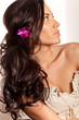 Portrait of young brunette woman with flower in curly hair