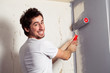 Smiling young man painting the wall with roll