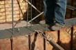 Construction worker standing atop a concrete wall newly poured Construction worker standing atop a concrete wall newly poured