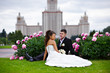 Romantic bride and groom in park surrounded by peony flowers
