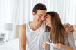 Photo: Cheerful couple with a pregnancy test in the bedroom Cheerful couple with a pregnancy test in the bedroom