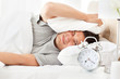 Stressed man looking at his alarm clock ringing
