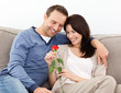 Portrait of a lovely couple looking at a red rose
