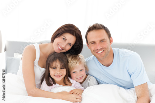 Foto: Portrait of a happy family sitting on the bed Portrait of a happy family sitting on the bed