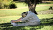 Old woman doing warm up sitting on the grass