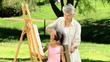 Young child painting a canvas with grandmother