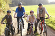 Young family pose with  bikes in park