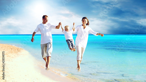 Photo: View of happy young family having fun on the beach View of happy young family having fun on the beach