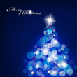 Christmas tree with blurred lights on blue background.
