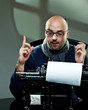 Old fashioned bald writer in glasses writing book