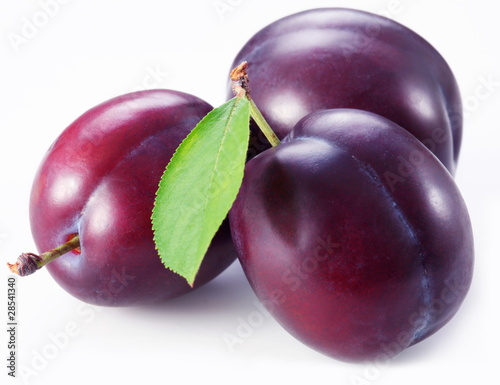 Foto: Three plums with leaves on white background. Three plums with leaves on white background.