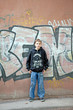 The teenager costs against a wall from graffiti.