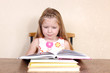 Little girl reading book in the kitchen against yellow wall at h Little girl reading book in the kitchen against yellow wall at h