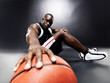 Successful young basketball player sitting with a ball