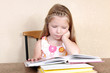 Little girl reading book against yellow wall at home