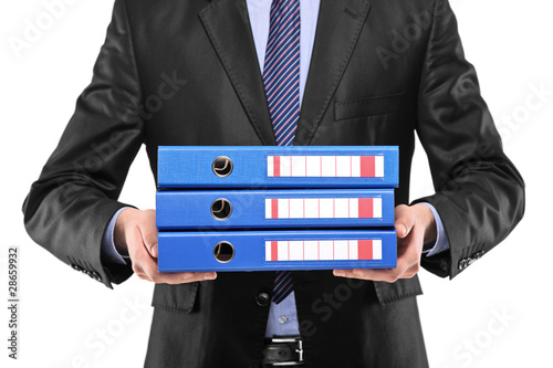 Photo: A close up of a businessman holding three blue folders A close up of a businessman holding three blue folders