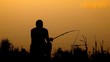 back view of fisherman sitting near pond in park
