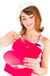 Cute girl in cap cutting valentine heart out of red paper