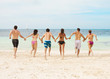 Photo: Group of young adults running together on the beach Group of young adults running together on the beach