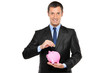 Businessman putting a coin into a piggy bank Businessman putting a coin into a piggy bank